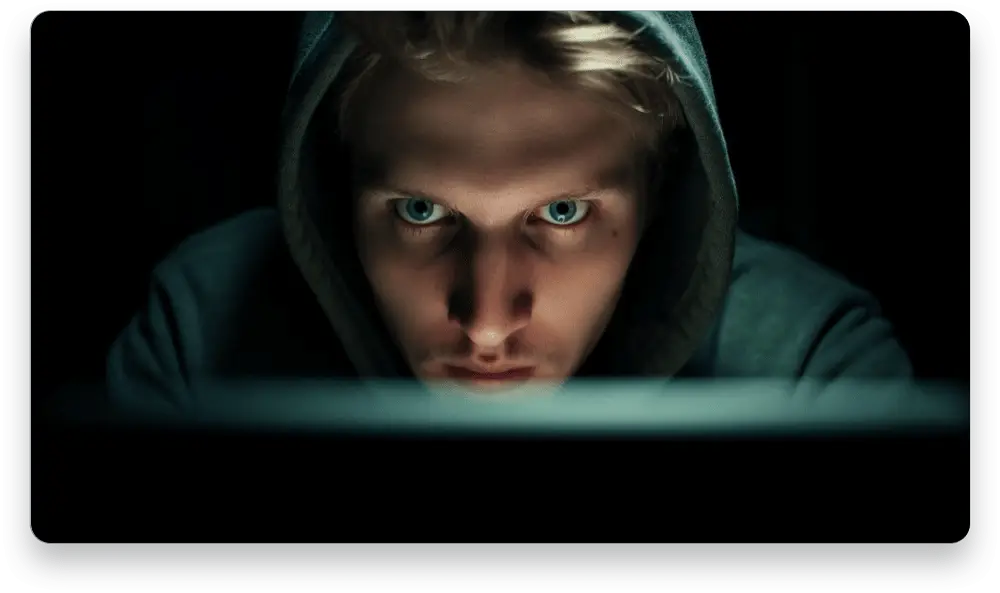 Person in a hoodie intensely focused on a glowing screen, symbolizing deep concentration and the pursuit of online profit with A.I